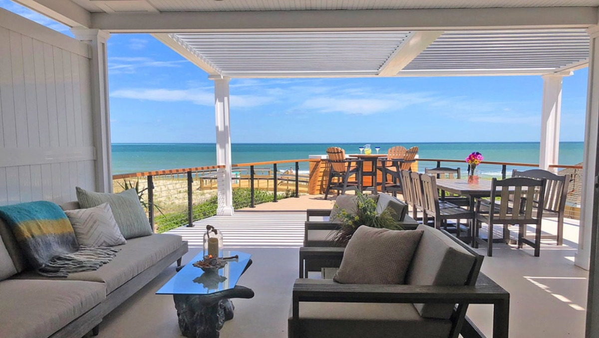 Retractable pergola providing shade over a waterfront patio at a coastal home in Ocean City Maryland overlooking the Atlantic Ocean.