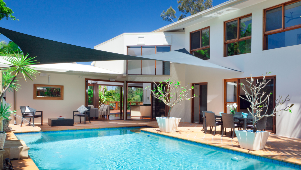 Contemporary home with multiple shade sails installed over pool and patio for sun protection and outdoor living