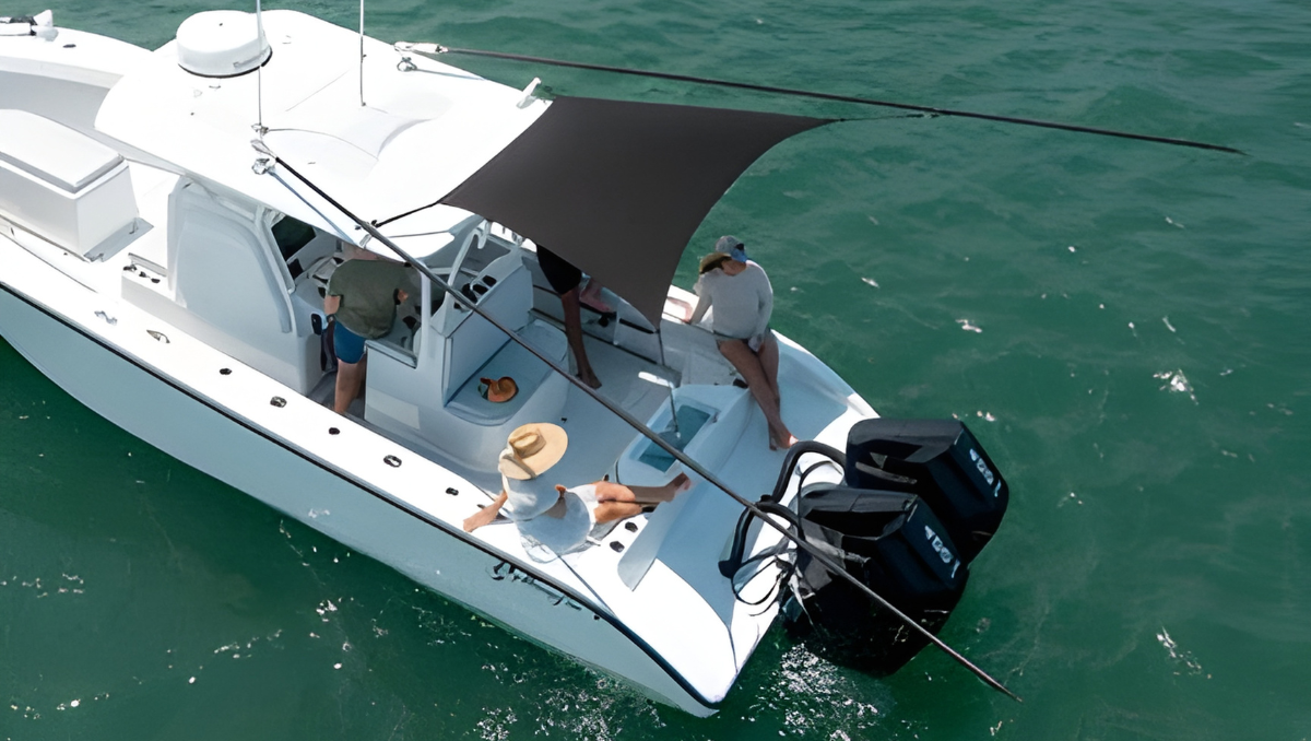 Small motorboat with a stretched black fly boat shade providing sun cover for passengers cruising on green-blue ocean water.