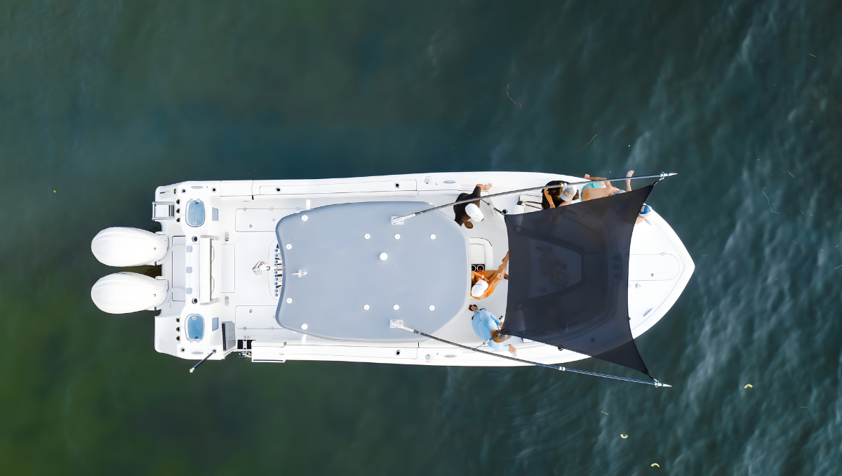Overhead drone view of a center console boat with a black fly shade stretched over the seating area on calm ocean water.