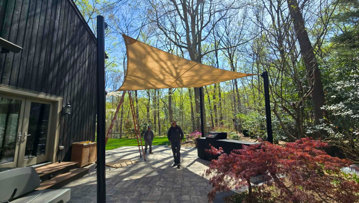 Shade sail installation training Maryland Delaware showing team learning how to tension and attach sail to posts in backyard setting