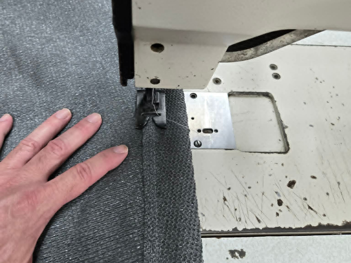Custom Shade Sail Fabrication Skilled technician sewing premium shade sail fabric during the manufacturing process for a custom shade sail installation.