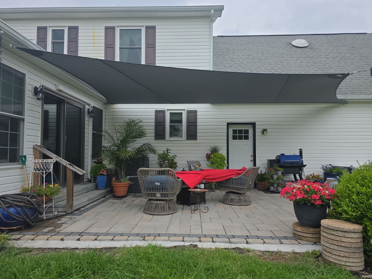 Front view of a custom charcoal shade sail installed over a residential patio in Bridgeville, DE.