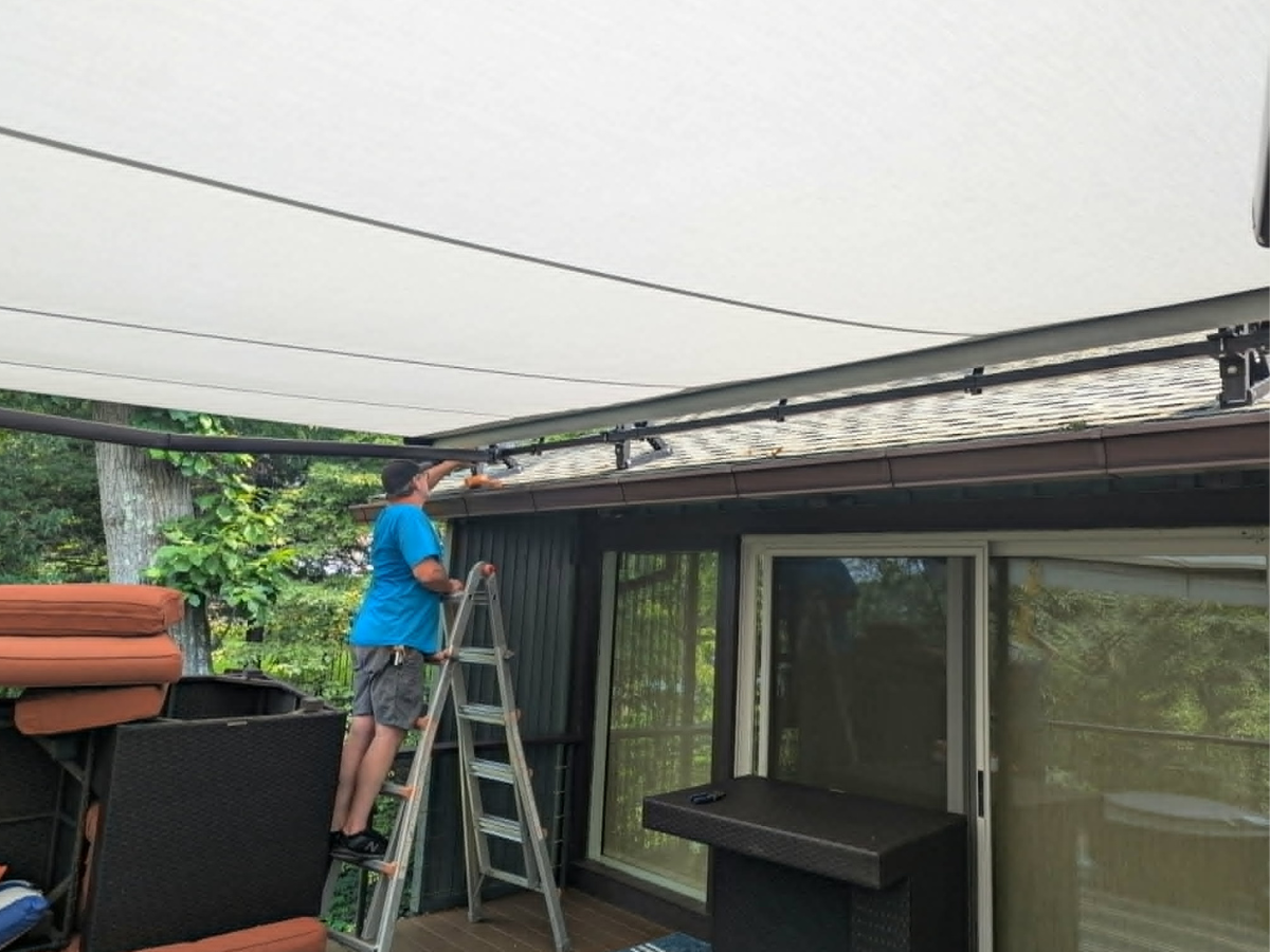 Shade Sail Systems technician installing a custom retractable awning on a residential deck in Falls Church, VA.