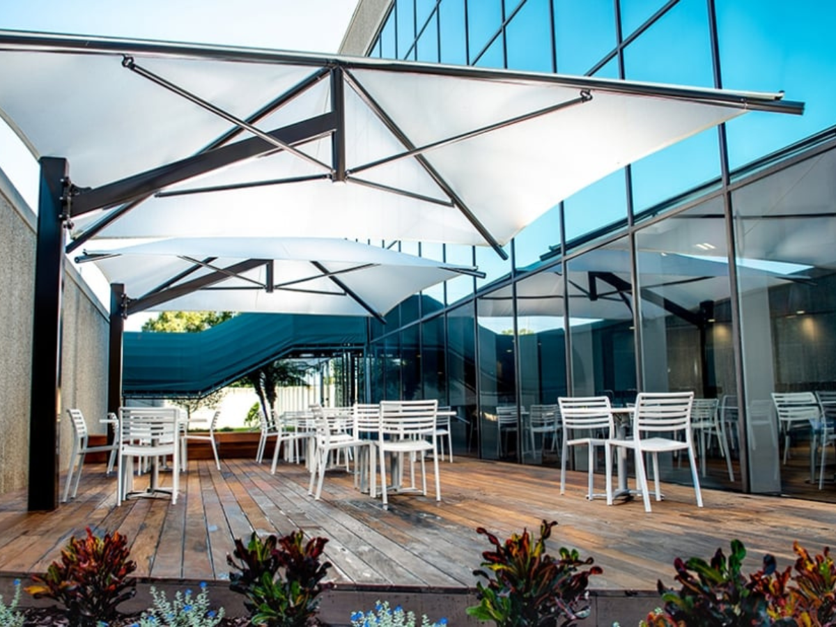 Custom cantilever shade structures providing outdoor seating shade at a commercial property.